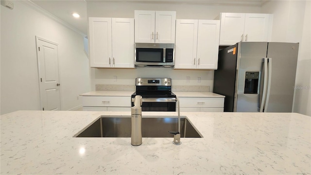 kitchen with stainless steel appliances, crown molding, and white cabinetry