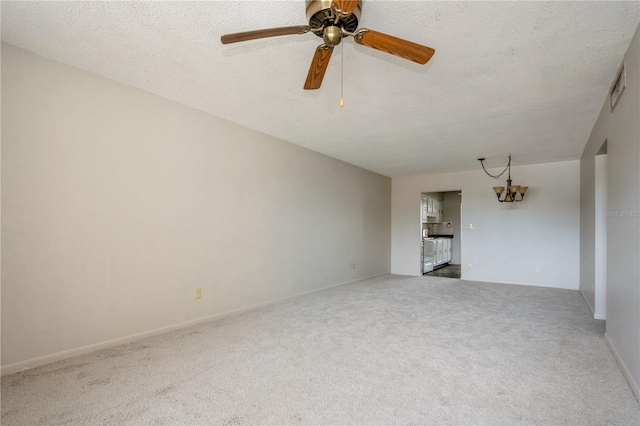 spare room with carpet, a textured ceiling, and ceiling fan with notable chandelier