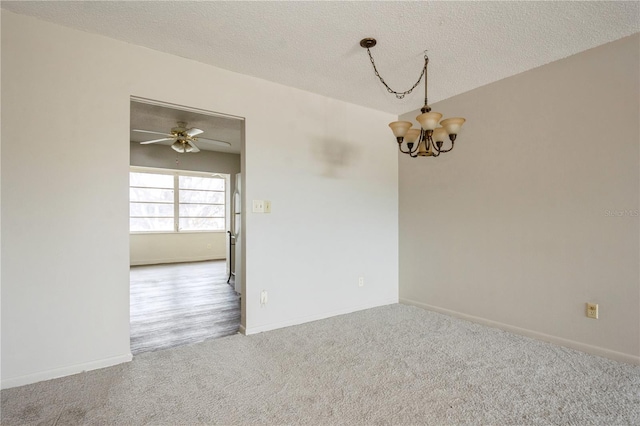 carpeted empty room featuring ceiling fan with notable chandelier and a textured ceiling