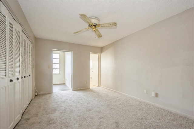 unfurnished bedroom with light carpet, a textured ceiling, and ceiling fan