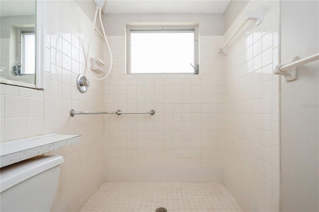 bathroom with a tile shower and toilet