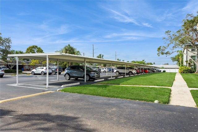 view of vehicle parking with a carport and a lawn