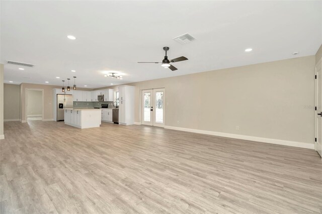 unfurnished living room with ceiling fan, light hardwood / wood-style floors, and french doors