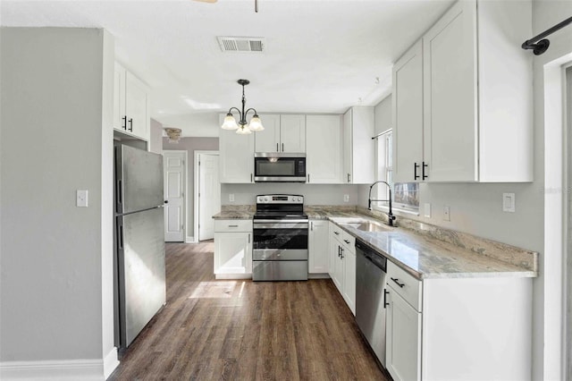 kitchen featuring appliances with stainless steel finishes, sink, pendant lighting, a notable chandelier, and white cabinets