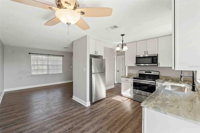 kitchen featuring pendant lighting, white cabinets, sink, light stone countertops, and appliances with stainless steel finishes