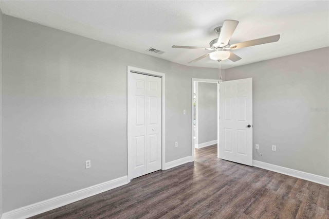 unfurnished bedroom featuring ceiling fan, dark hardwood / wood-style flooring, and a closet