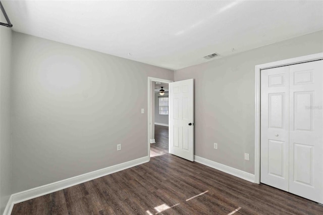 unfurnished bedroom with dark wood-type flooring and a closet