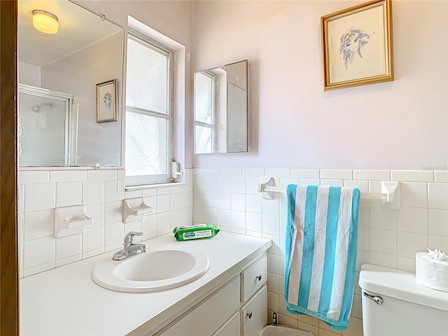 bathroom with walk in shower, vanity, tile walls, and toilet