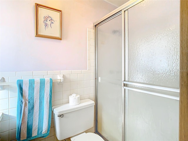 bathroom with a shower with door, toilet, and tile walls