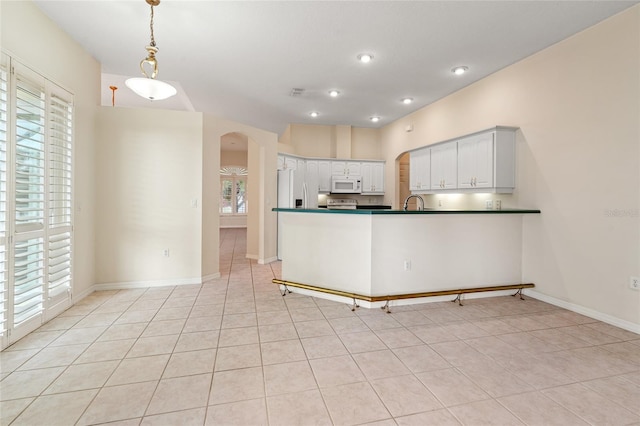 kitchen featuring white appliances, hanging light fixtures, light tile patterned floors, white cabinetry, and kitchen peninsula