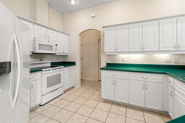 kitchen with white cabinets, light tile patterned flooring, and white appliances