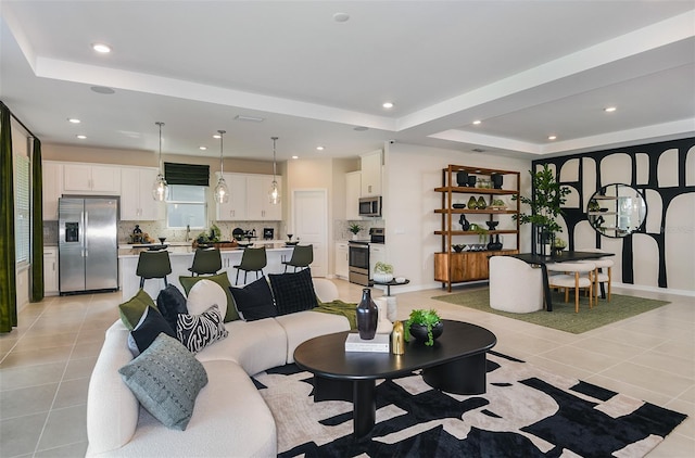 living room with light tile patterned floors, a raised ceiling, and sink