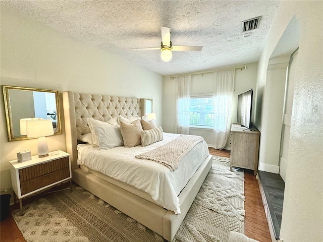 bedroom featuring ceiling fan, wood-type flooring, and a textured ceiling