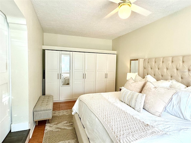 bedroom featuring a closet, ceiling fan, dark hardwood / wood-style flooring, and a textured ceiling