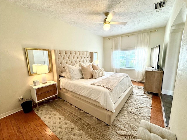 bedroom featuring hardwood / wood-style floors, a textured ceiling, and ceiling fan