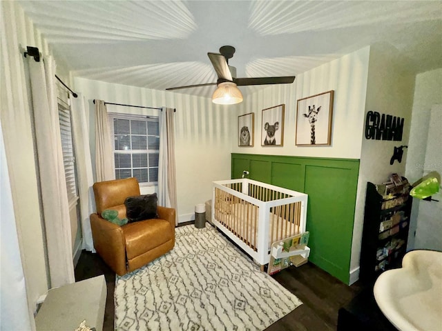 bedroom featuring a crib, wood-type flooring, and ceiling fan