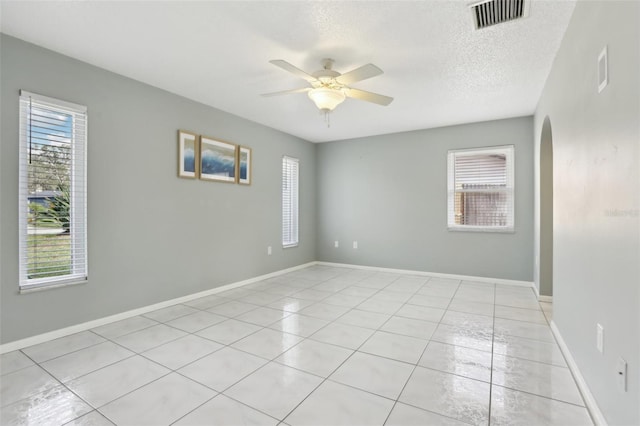 empty room with ceiling fan, light tile patterned flooring, and a textured ceiling