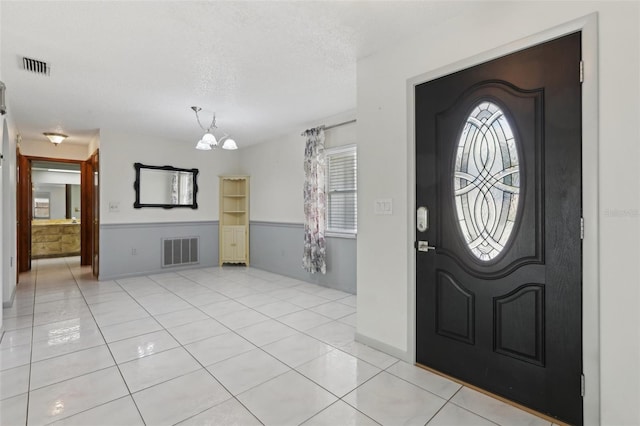 entrance foyer with a notable chandelier, light tile patterned floors, and a textured ceiling