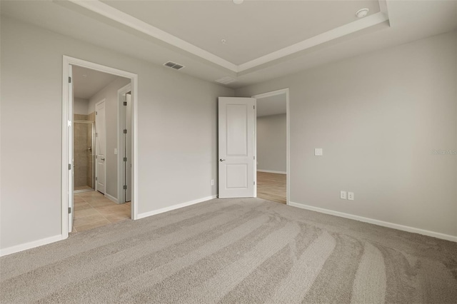 unfurnished bedroom featuring a raised ceiling and light carpet