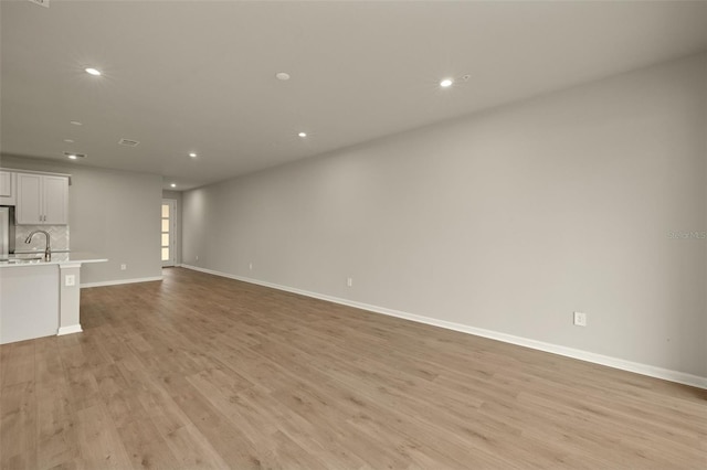 unfurnished living room featuring sink and light hardwood / wood-style floors