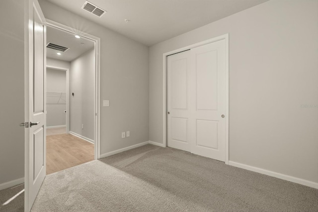 unfurnished bedroom with light colored carpet and a closet