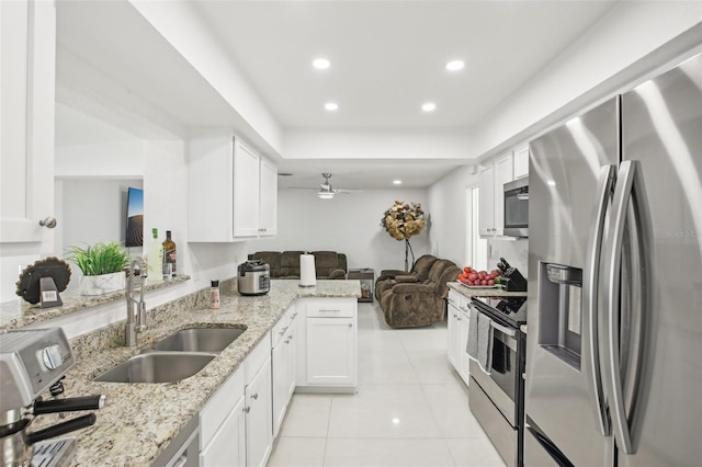 kitchen with light stone countertops, kitchen peninsula, white cabinetry, and stainless steel appliances