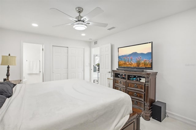 bedroom with light carpet, a closet, ensuite bath, and ceiling fan