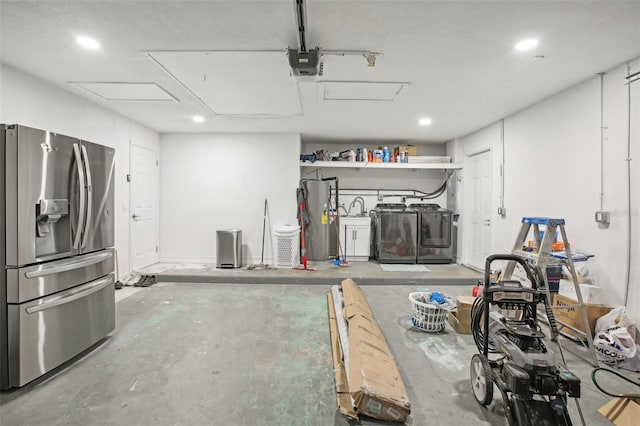 garage with washer and clothes dryer, stainless steel fridge, a garage door opener, and water heater