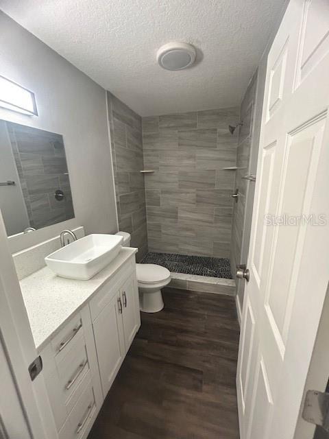 bathroom with vanity, hardwood / wood-style floors, a textured ceiling, and toilet