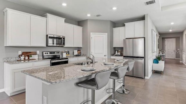 16018 10th Ave E, Bradenton, FL 34212 - kitchen with stainless steel appliances, an island with sink, white cabinetry, and recessed lighting