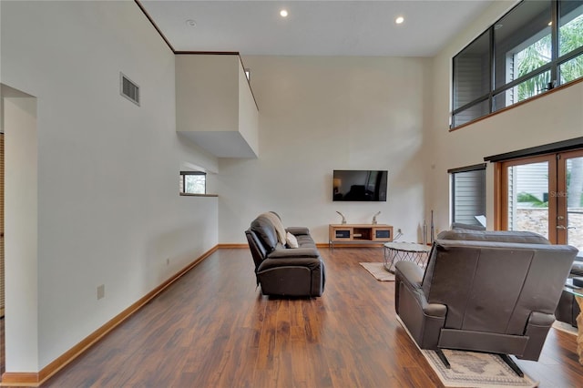 living room featuring dark hardwood / wood-style flooring and a towering ceiling