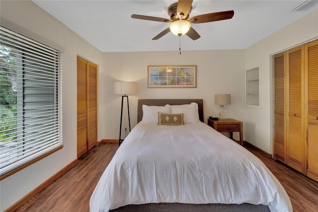 bedroom featuring hardwood / wood-style flooring, ceiling fan, and multiple closets