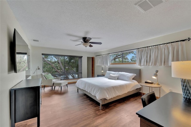 bedroom with ceiling fan, a textured ceiling, and hardwood / wood-style flooring