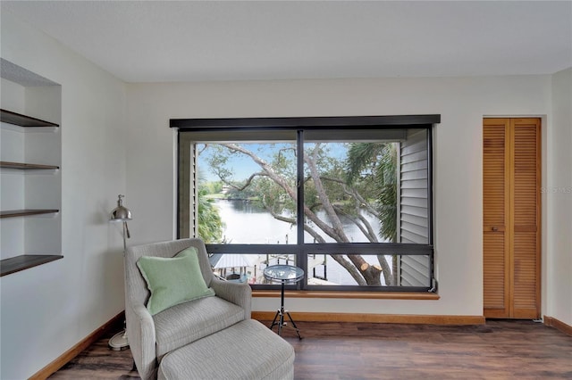 sitting room with a water view, a wealth of natural light, and dark hardwood / wood-style floors