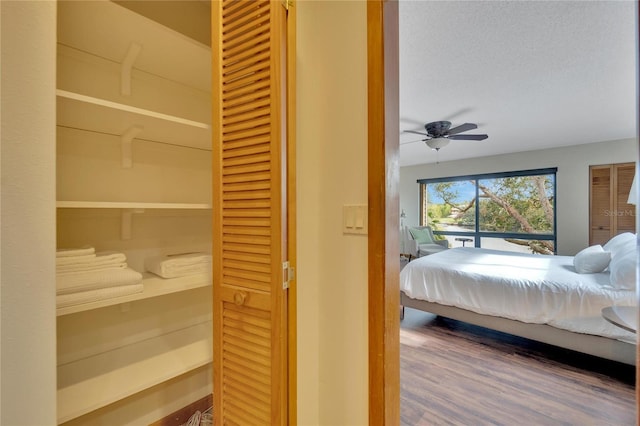 bedroom with ceiling fan, hardwood / wood-style floors, and a textured ceiling