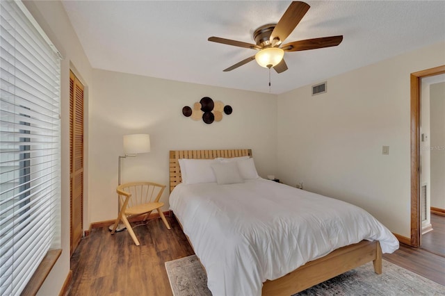 bedroom featuring multiple windows, a closet, dark wood-type flooring, and ceiling fan