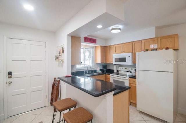 kitchen featuring sink, kitchen peninsula, white appliances, a breakfast bar area, and light tile patterned floors