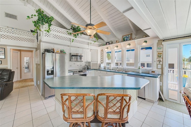 kitchen with a kitchen bar, appliances with stainless steel finishes, ceiling fan, high vaulted ceiling, and white cabinetry