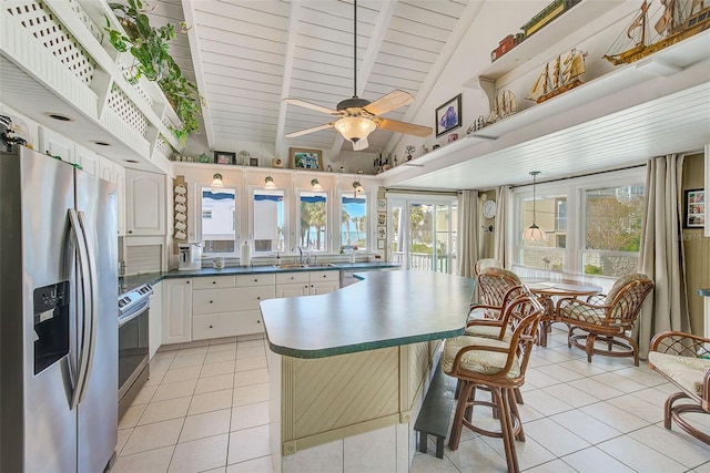 kitchen featuring appliances with stainless steel finishes, ceiling fan, sink, vaulted ceiling with beams, and white cabinetry