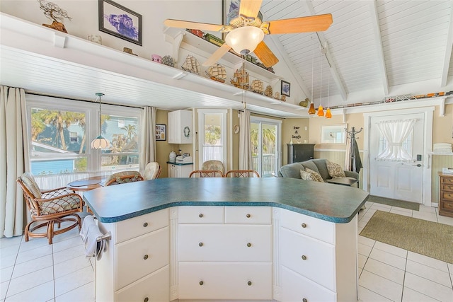 kitchen with pendant lighting, beamed ceiling, white cabinets, and light tile patterned flooring