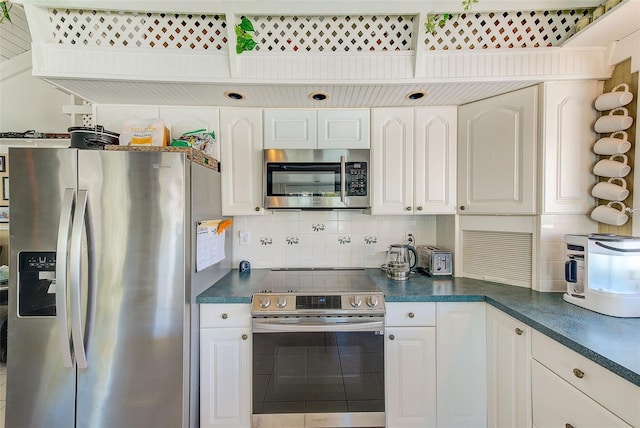 kitchen with backsplash, white cabinets, and stainless steel appliances