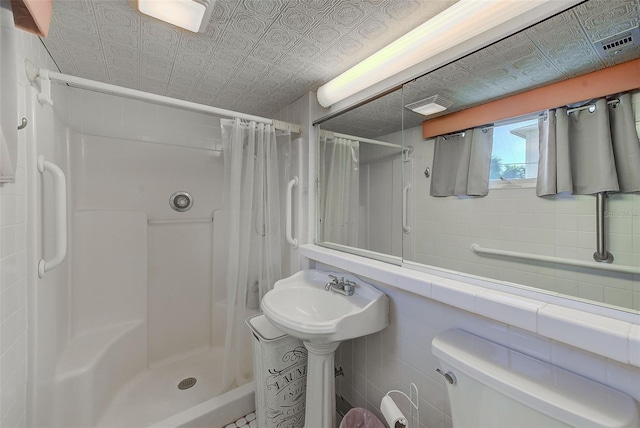 bathroom with a shower with shower curtain, toilet, and tile walls