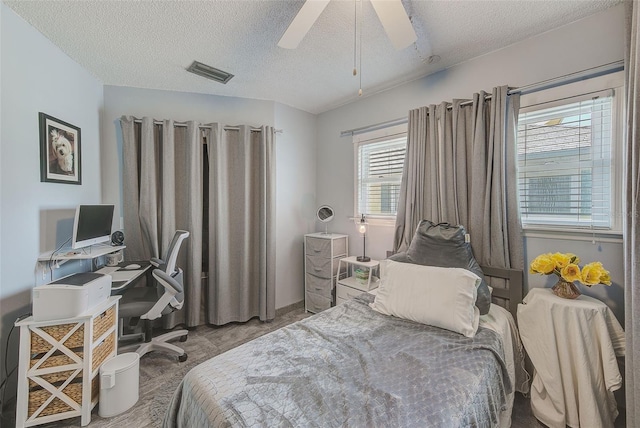 carpeted bedroom with ceiling fan, a textured ceiling, and multiple windows