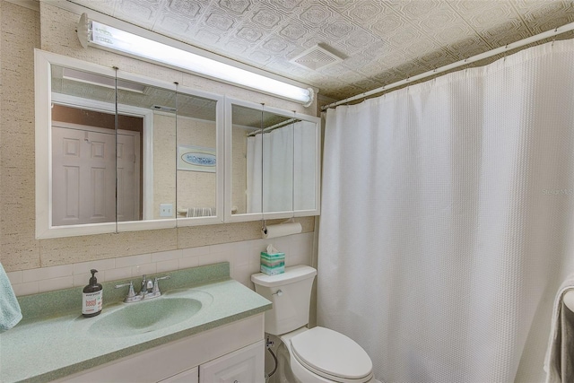 bathroom with walk in shower, vanity, toilet, and tile walls