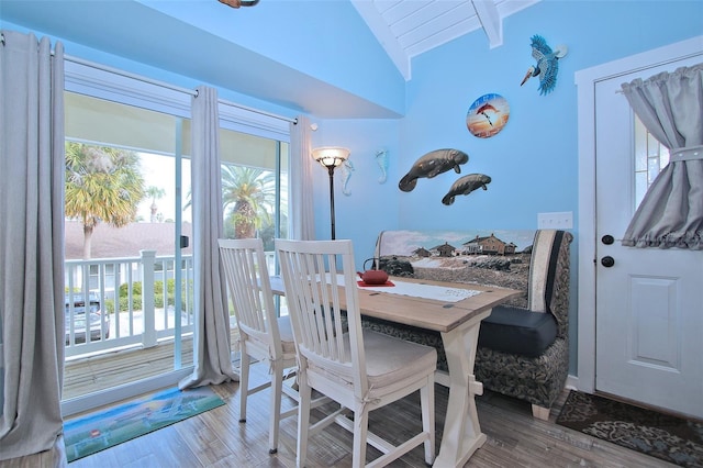 dining area with wood-type flooring and lofted ceiling with beams