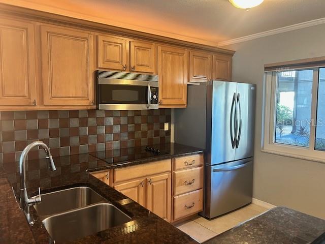 kitchen featuring backsplash, dark stone countertops, sink, and appliances with stainless steel finishes