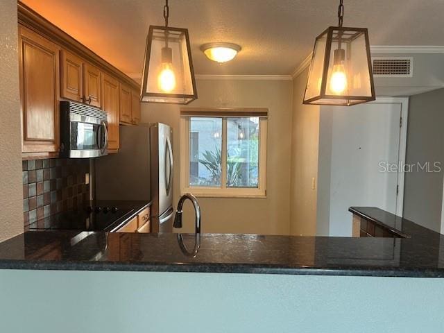 kitchen with kitchen peninsula, decorative backsplash, crown molding, sink, and decorative light fixtures