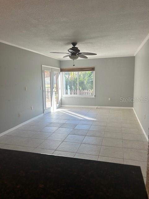 empty room featuring french doors, ceiling fan, light tile patterned floors, a textured ceiling, and ornamental molding