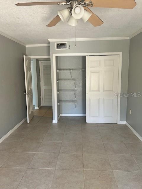 unfurnished bedroom with a textured ceiling, ceiling fan, crown molding, and a closet