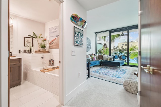 bathroom featuring a relaxing tiled tub, vanity, tile patterned floors, and expansive windows